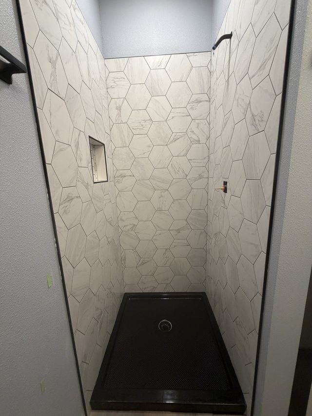 white marble hexagon tile shower stall with black shower pan