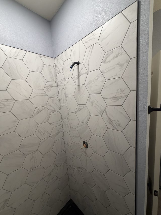 white marble hexagon tile shower walls with valve
