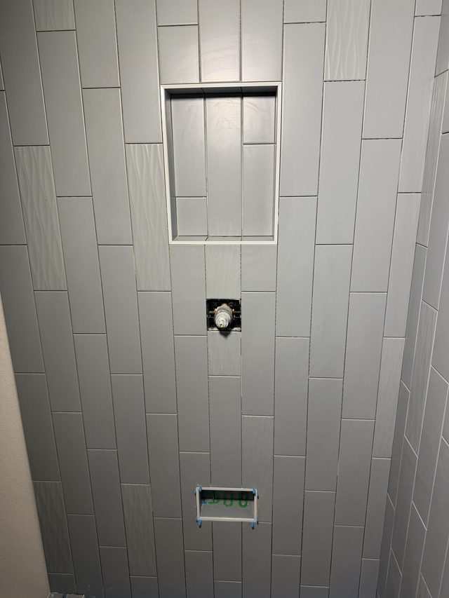 gray vertical tile shower wall with niche and valve rough-in