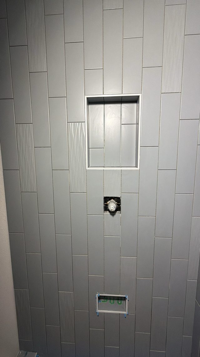 gray vertical tile shower wall with niche and valve
