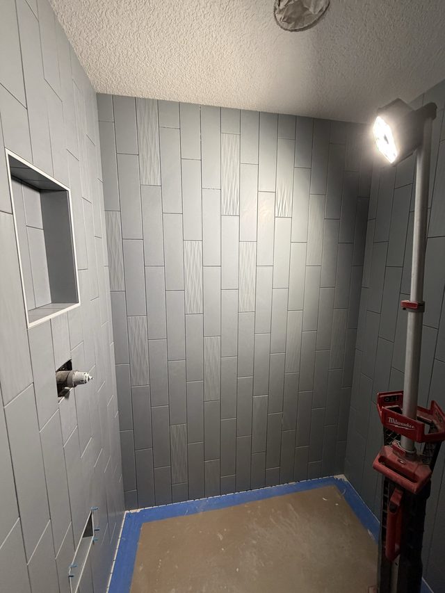 gray tile shower in progress with niche, work light