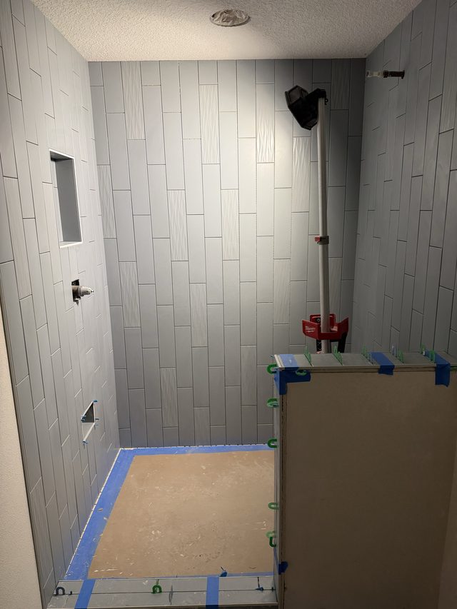 gray tile shower in progress with niche and rough-in
