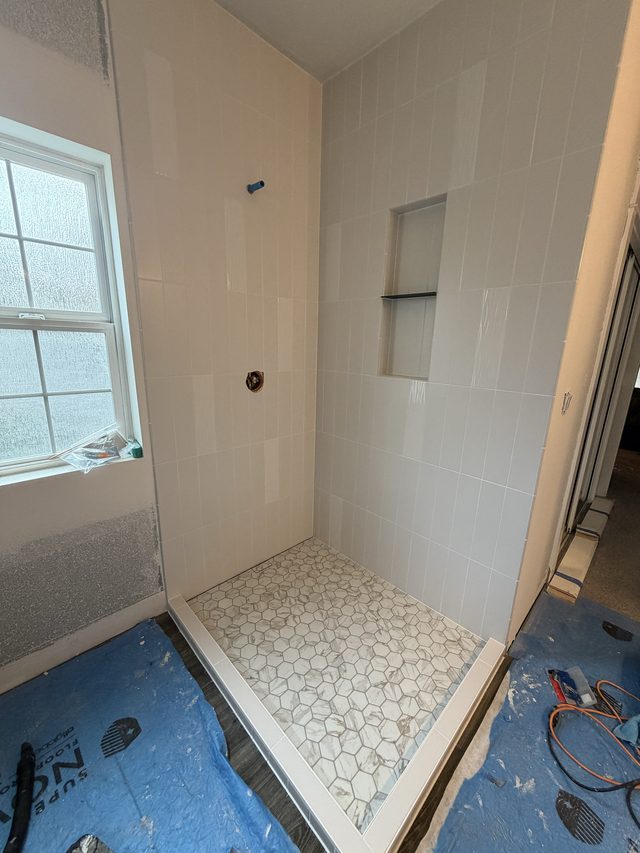 white tile shower with hexagon mosaic floor and window