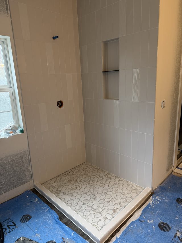 white tile shower with hex mosaic floor and niche