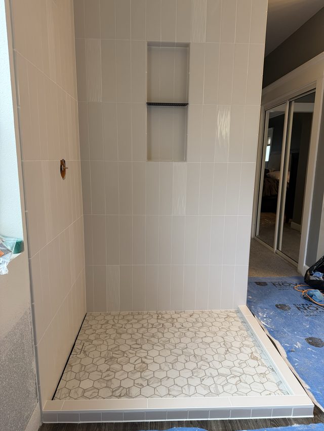 white tile shower with hex mosaic floor and niche
