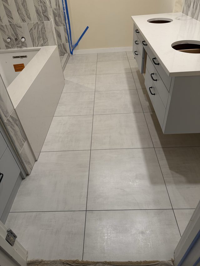 gray tile bathroom floor with double vanity and tiled shower in progress