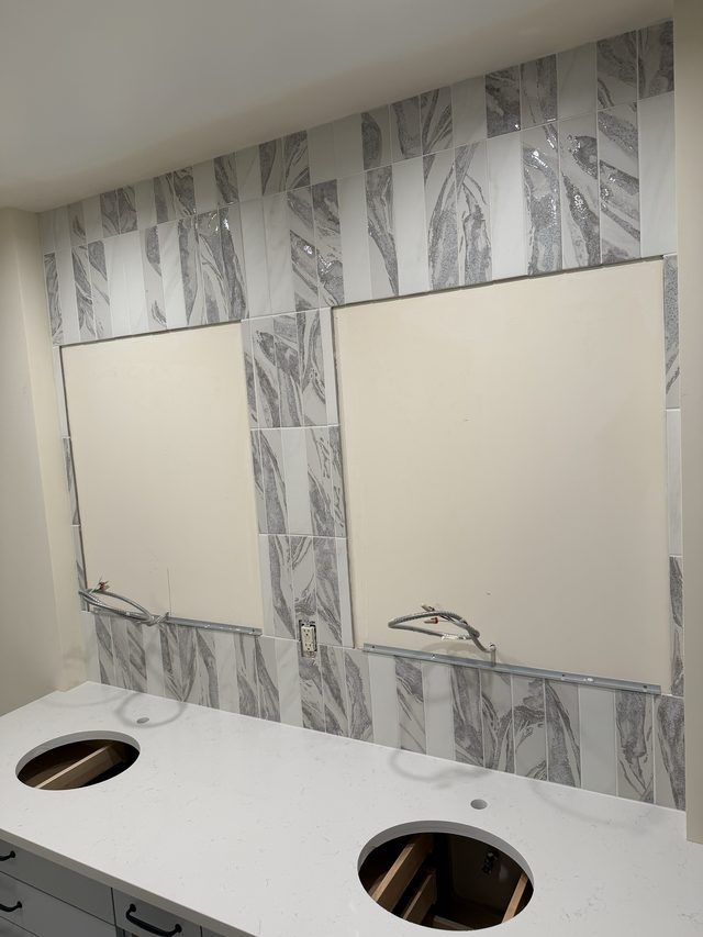 bathroom vanity wall with gray marble-look feature tile, double sink cutouts