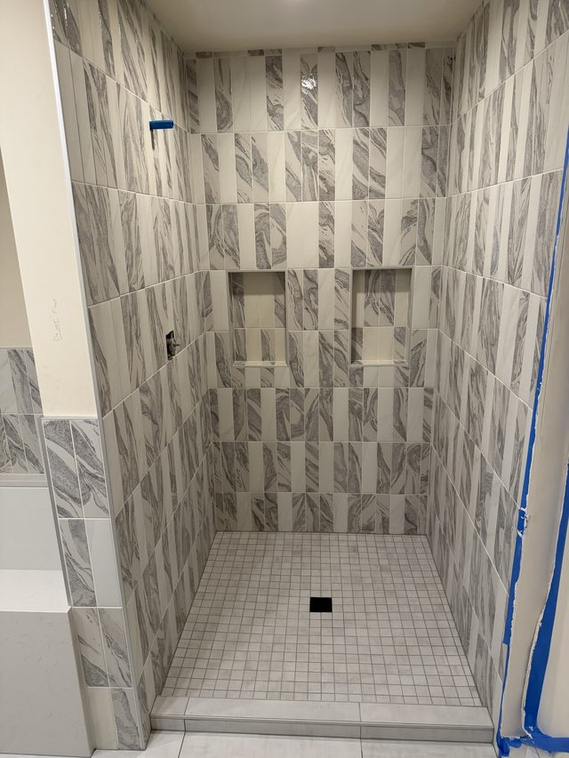 walk-in shower with gray marble-look tile, niche, white mosaic floor pan