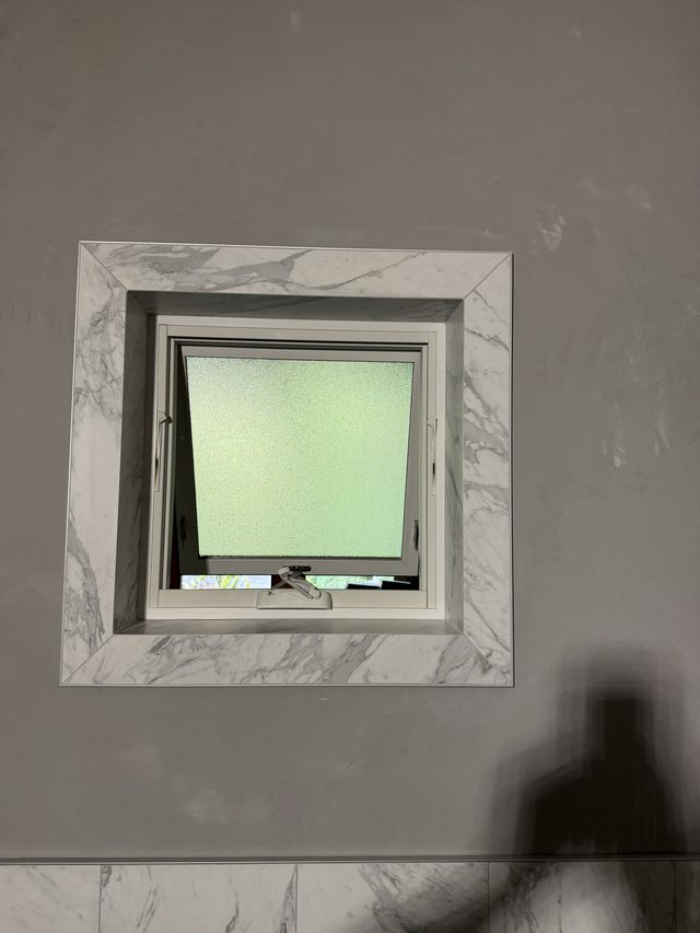 marble-tiled bathroom wall framing a frosted window