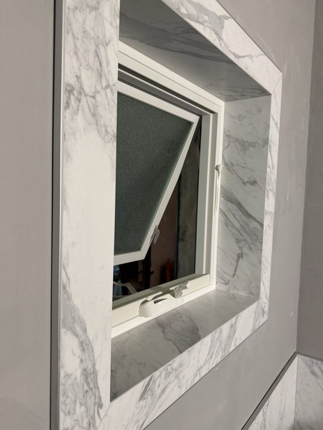 marble-tiled bathroom wall with awning window