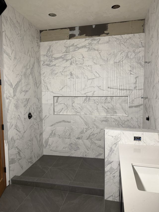 marble walk-in shower with bench, niche and adjacent vanity