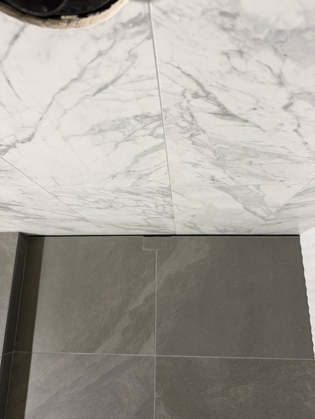 marble wall tile meeting gray bathroom floor tile