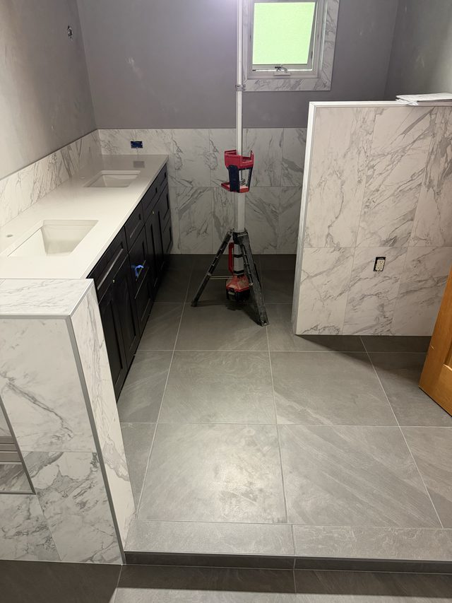 bathroom with dark double vanity, marble walls and gray floor tile