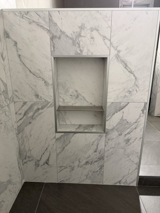 marble shower wall with recessed niche and dark shower floor