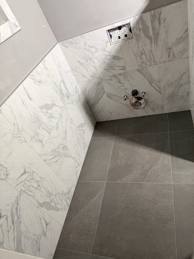 marble shower walls with valve and gray floor tile