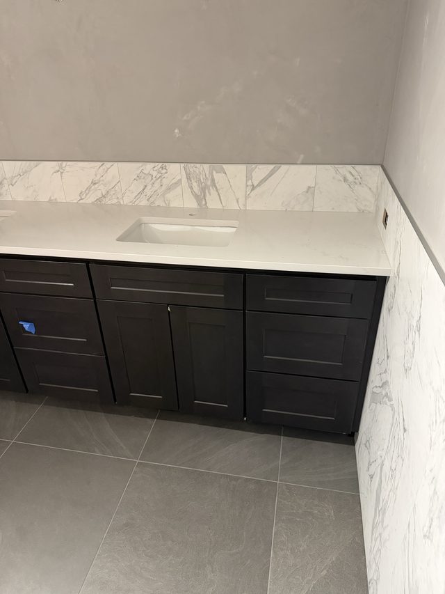 bathroom vanity with dark cabinets, white countertop and undermount sink