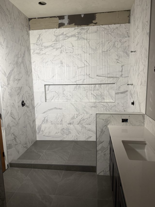marble walk-in shower with bench, linear niche and vanity