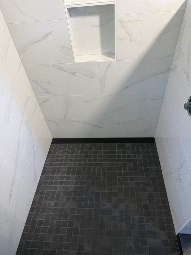 marble shower with niche and dark mosaic shower floor