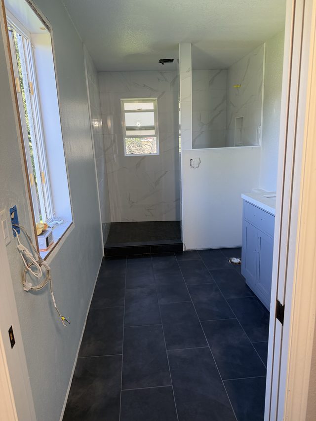 bathroom with walk-in shower, dark floor tile and blue vanity