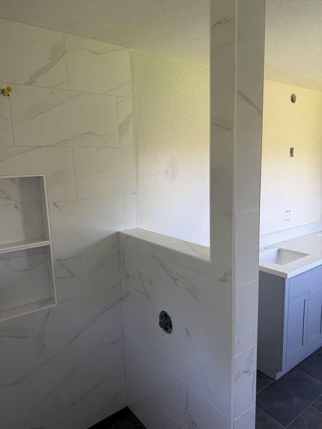 marble shower with niche and valve, vanity visible beyond