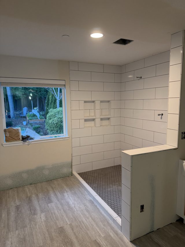 white subway tile walk-in shower with niche and gray hex floor
