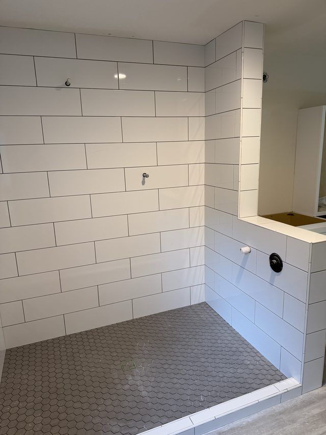 white subway tile walk-in shower with gray hex tile floor