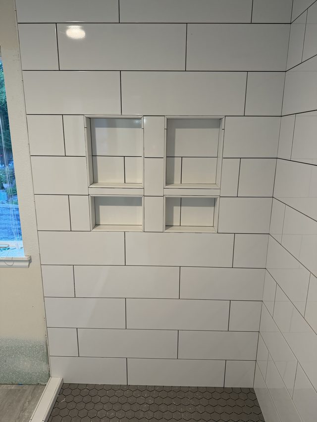 white subway tile shower wall with cubby niches, hex floor