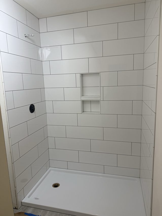 white subway tile shower with white shower pan and niche