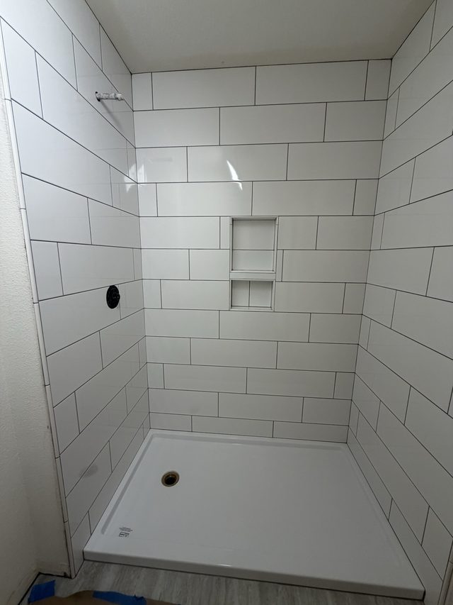 white subway tile shower with white shower pan and niche