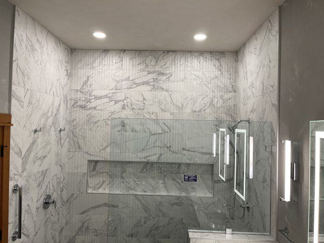 marble tile walk-in shower with glass enclosure and long niche