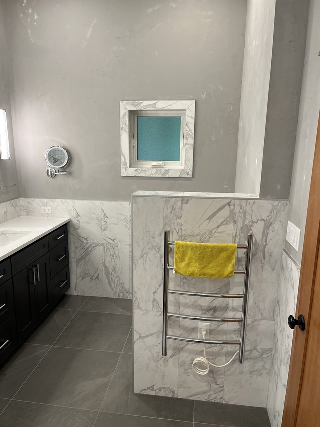 marble-clad bathroom with towel warmer, vanity and window