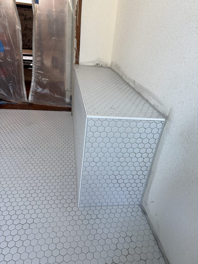 white hex tile floor and tiled shower bench/curb in wet area