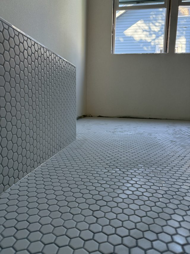 white hexagon mosaic floor with white penny-round tile wainscot, bathroom under construction
