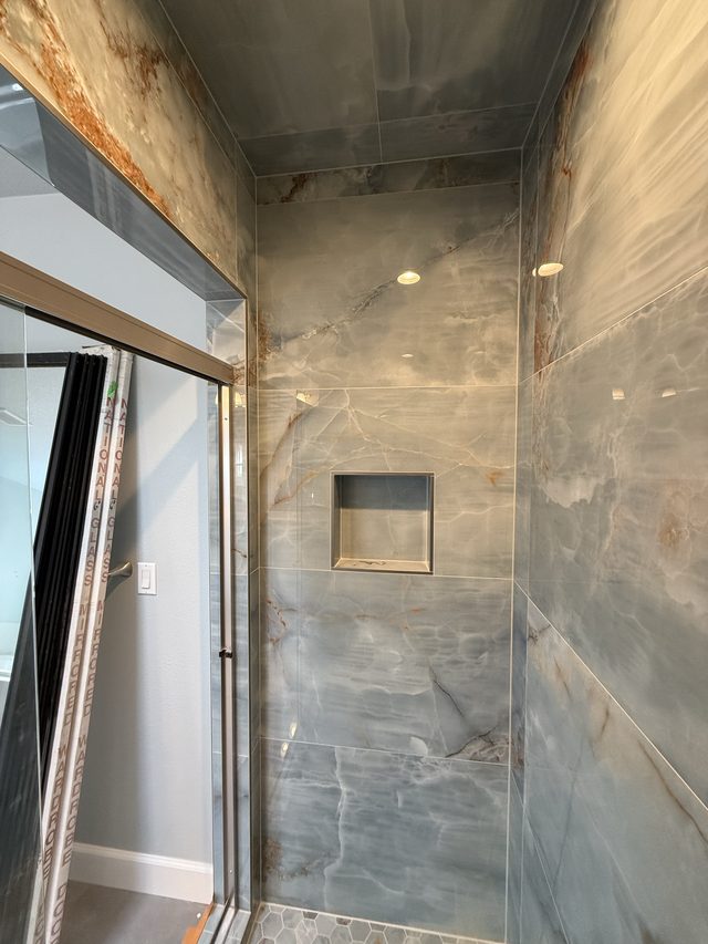 blue onyx-look tile shower with niche and glass door