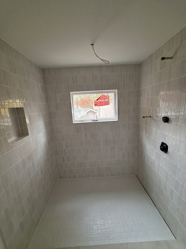 gray tile shower with fixtures, niche and window