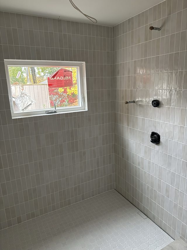 gray tile shower with valve fixtures and window