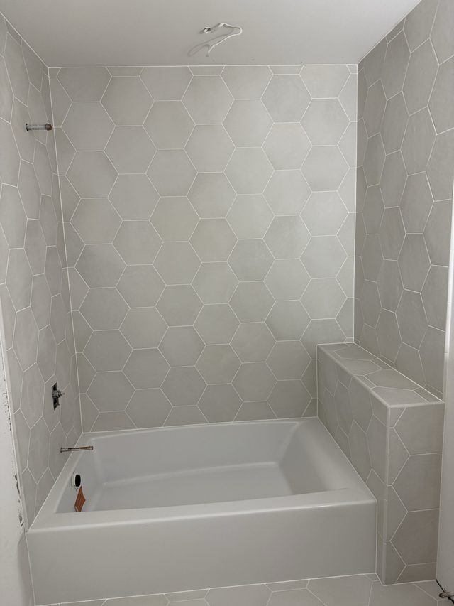 white hexagon tile tub surround with bathtub and tiled bench