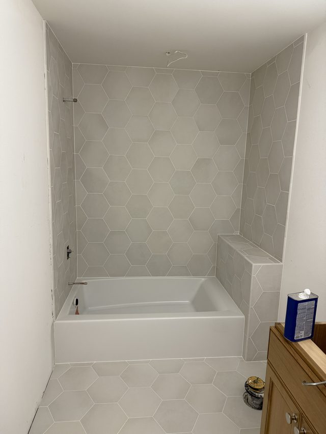 hexagon tile tub surround with bathtub, bench and vanity