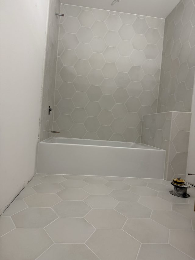 hexagon tile tub surround with bathtub and tiled floor