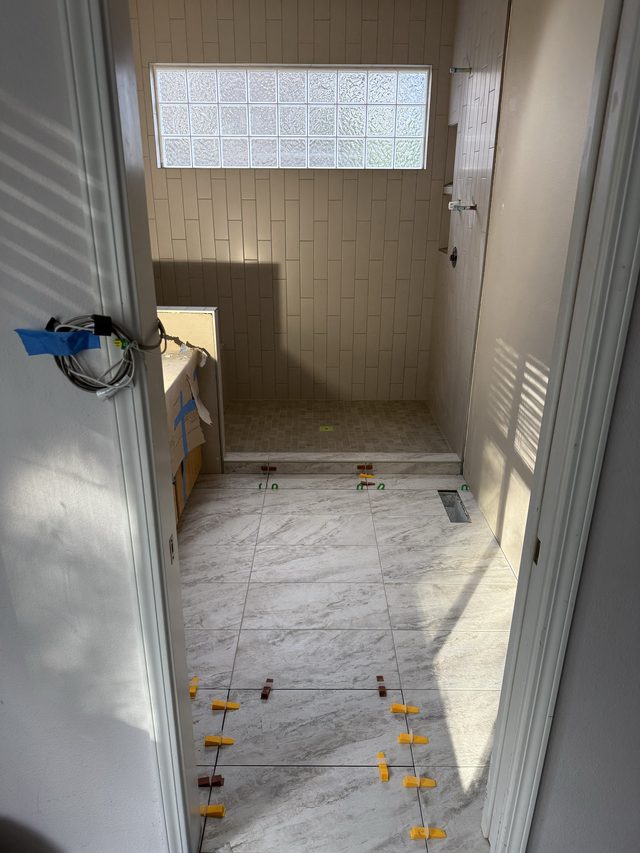bathroom under renovation, marble floor tile and tiled shower with glass-block window