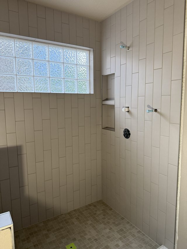 tiled shower with niche, fixtures and glass-block window