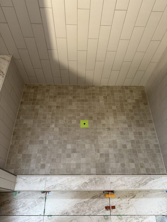 mosaic shower floor with tiled walls and ceiling
