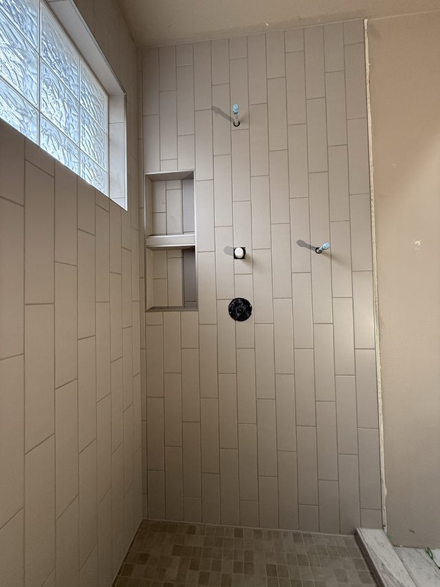 tiled shower with niche, valve fixtures and glass-block window