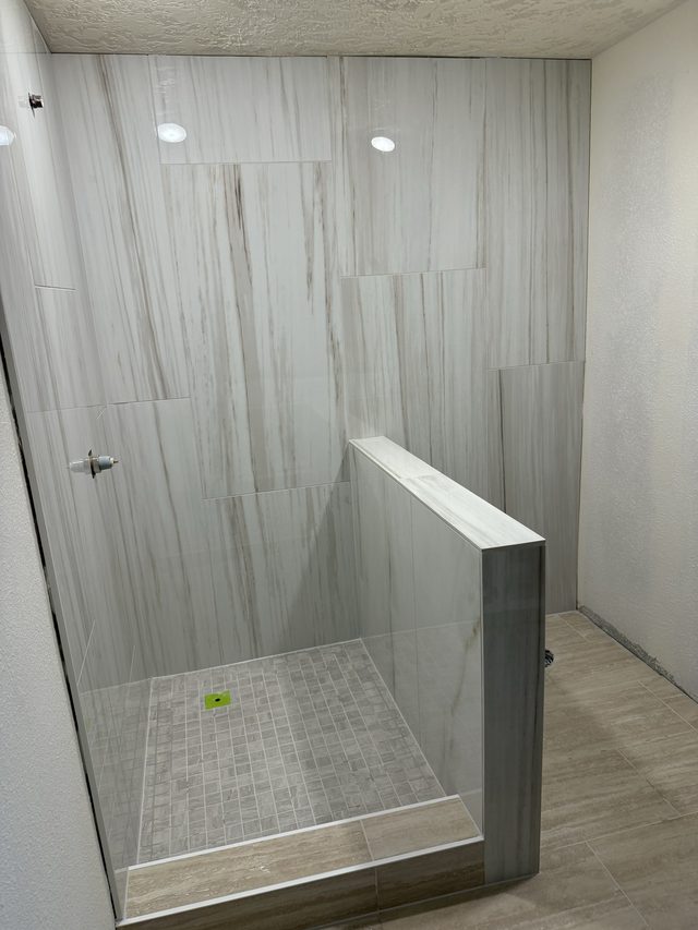tiled walk-in shower with glass panel and mosaic floor