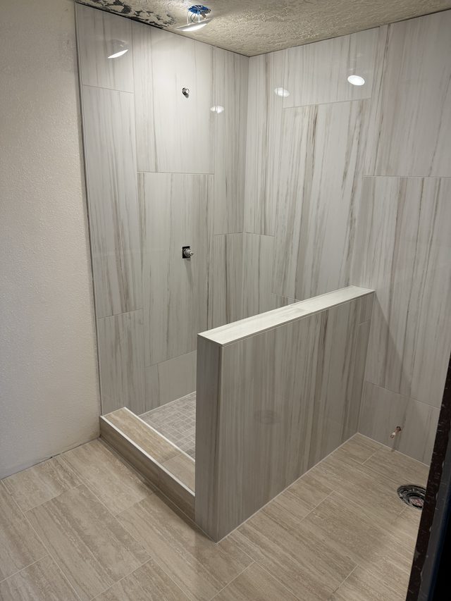 tiled walk-in shower with pony wall and mosaic pan