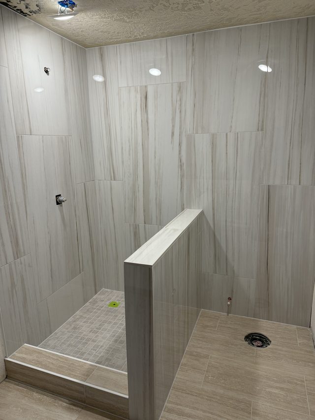 tiled walk-in shower with pony wall and recessed lights