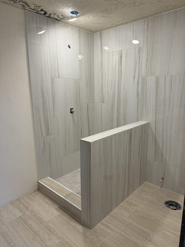 tiled walk-in shower with half wall and drain
