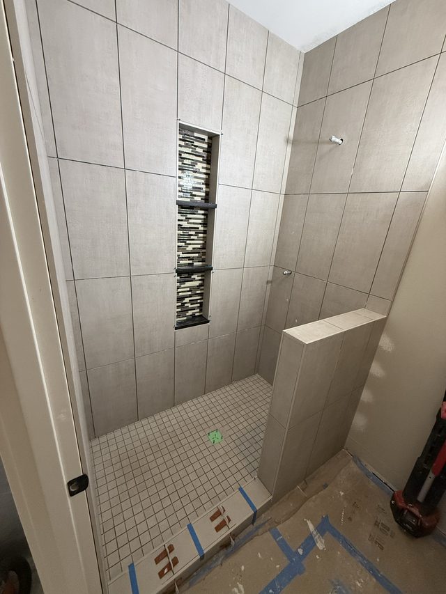 tiled walk-in shower with linear mosaic niche and pony wall