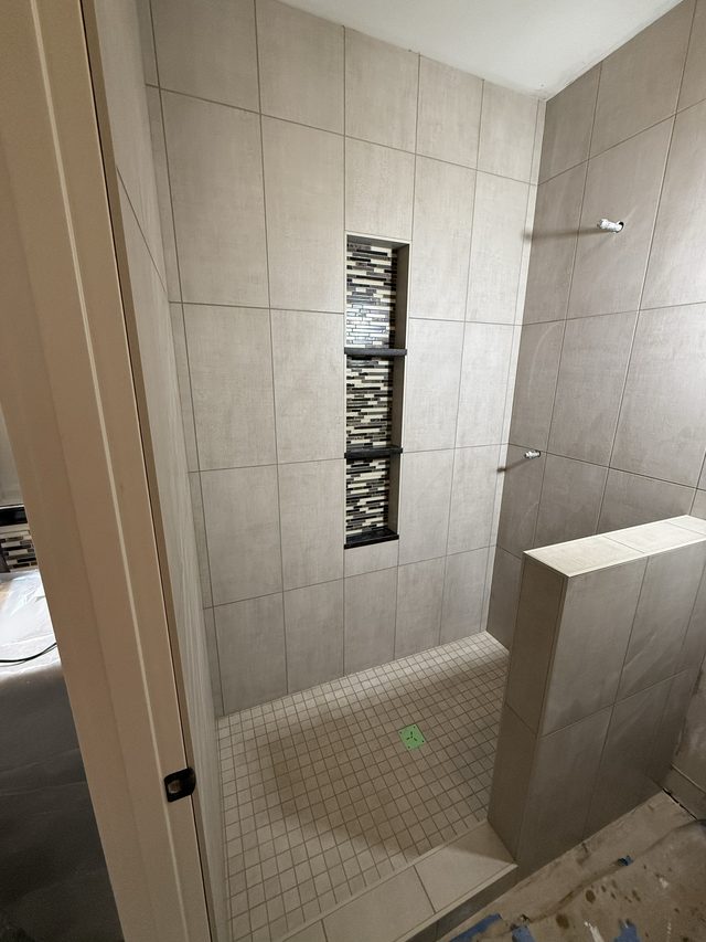 tiled walk-in shower with mosaic niche and pony wall