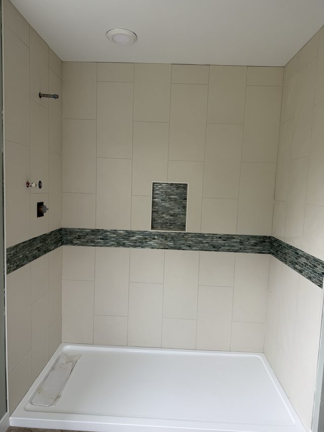 tiled shower with green mosaic accent band, niche, white pan